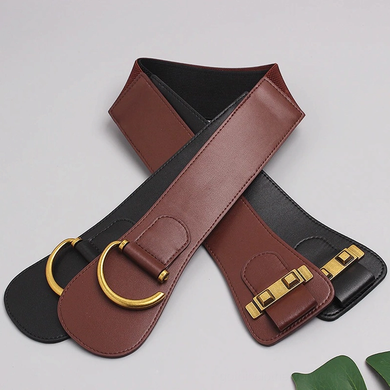 Two gothic corset wide belts crossed display with antique gold D-ring buckles on natural background