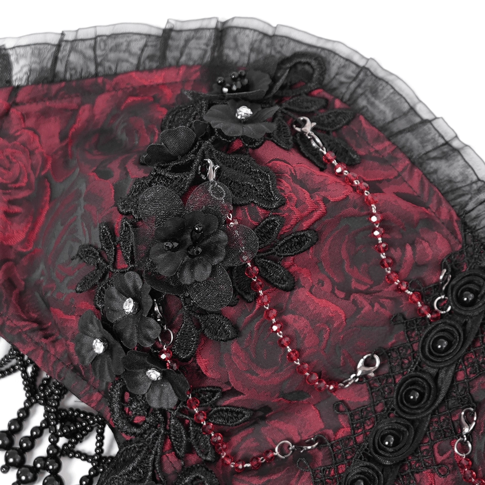 Close-up macro shot of gothic dress bust detailing showing black floral appliqué and beaded chains