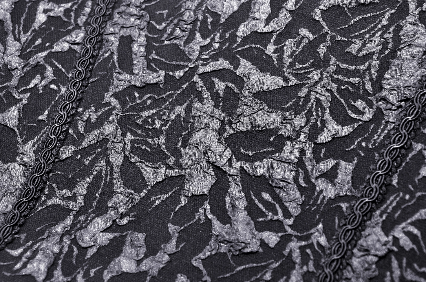 Macro fabric detail of gothic corset showing embossed floral lace texture and chain link lace trim