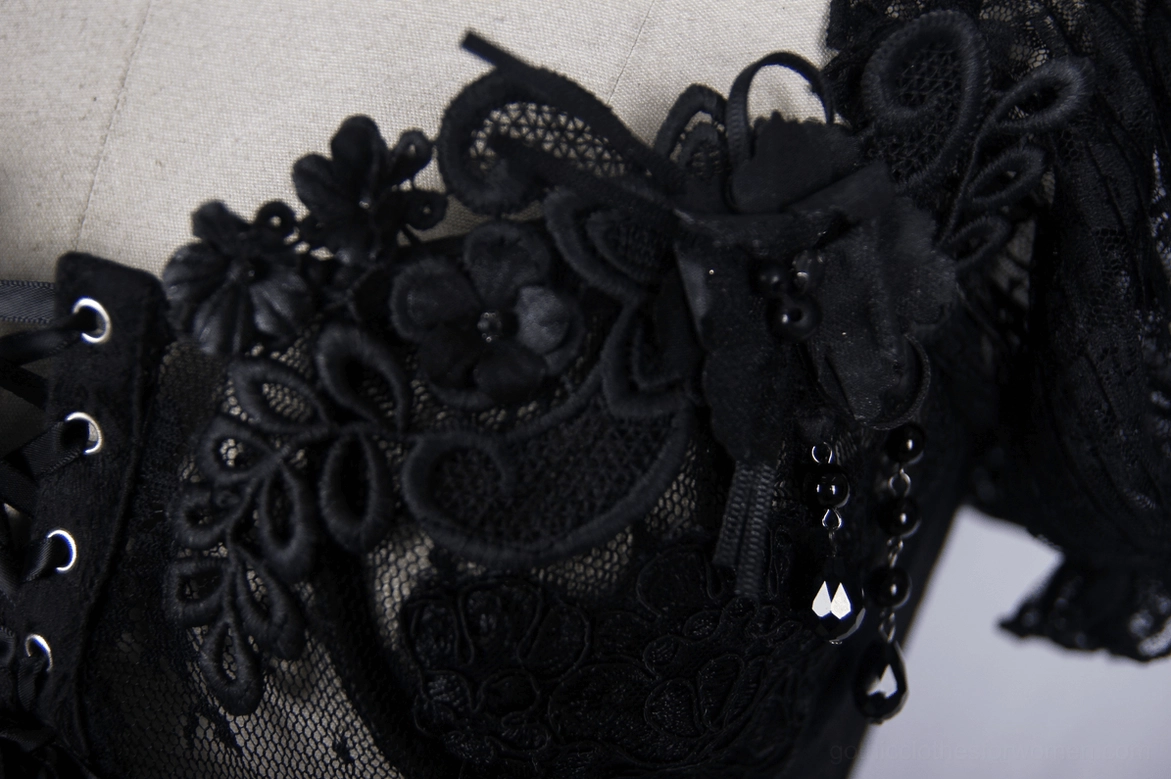 Close-up detail of black gothic corset front, floral lace appliqué with bead accents and lace bow embellishment