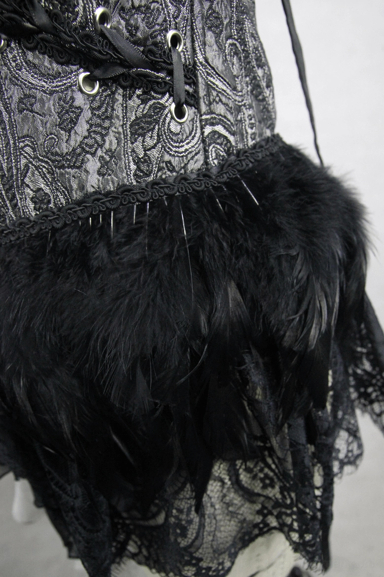 Close-up detail of gothic corset hem with black feather trim and metal lace-up eyelets