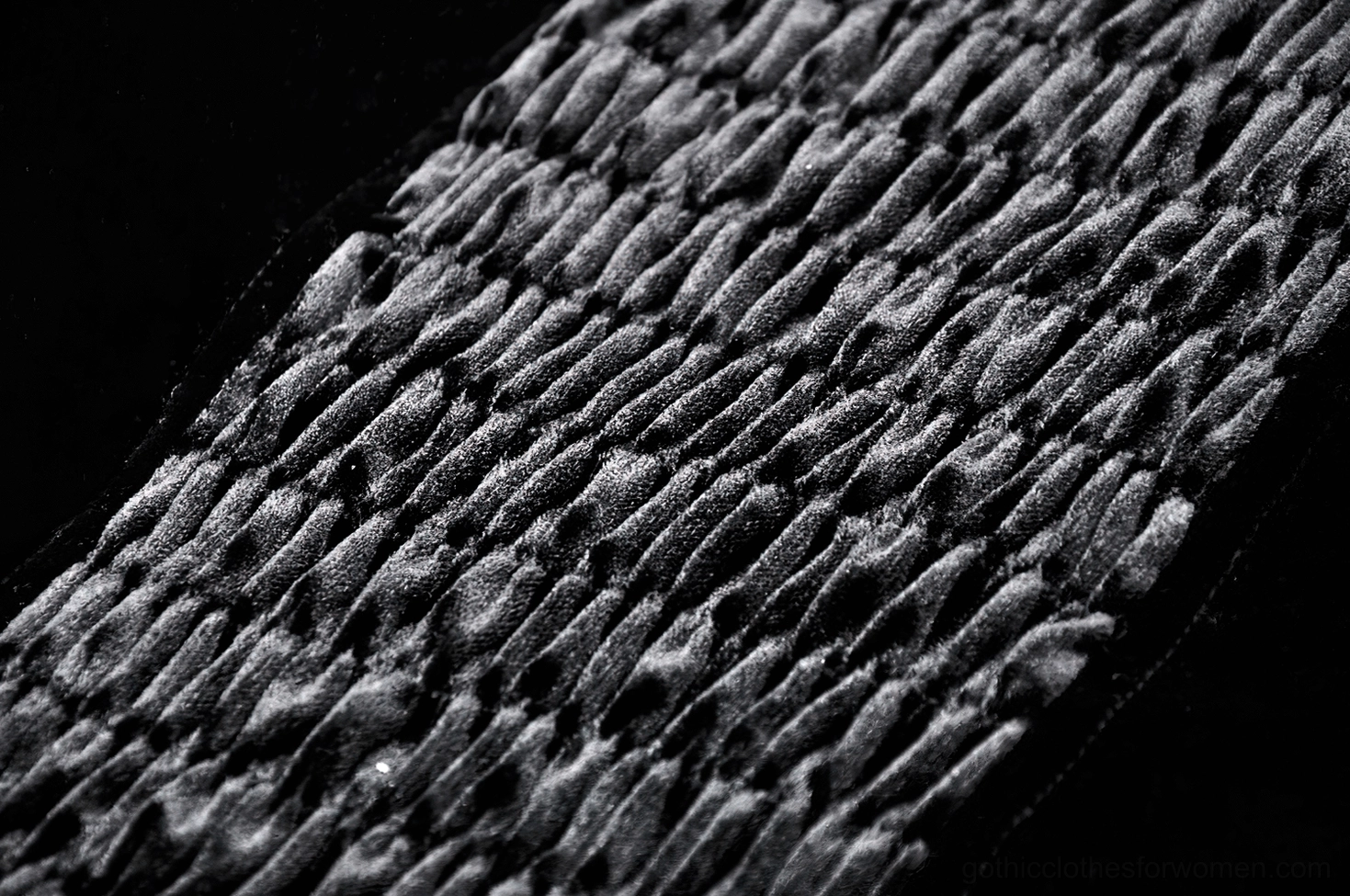 Macro texture detail of matte velvet fabric on gothic corset, ruched dark grey-black tone in close-up
