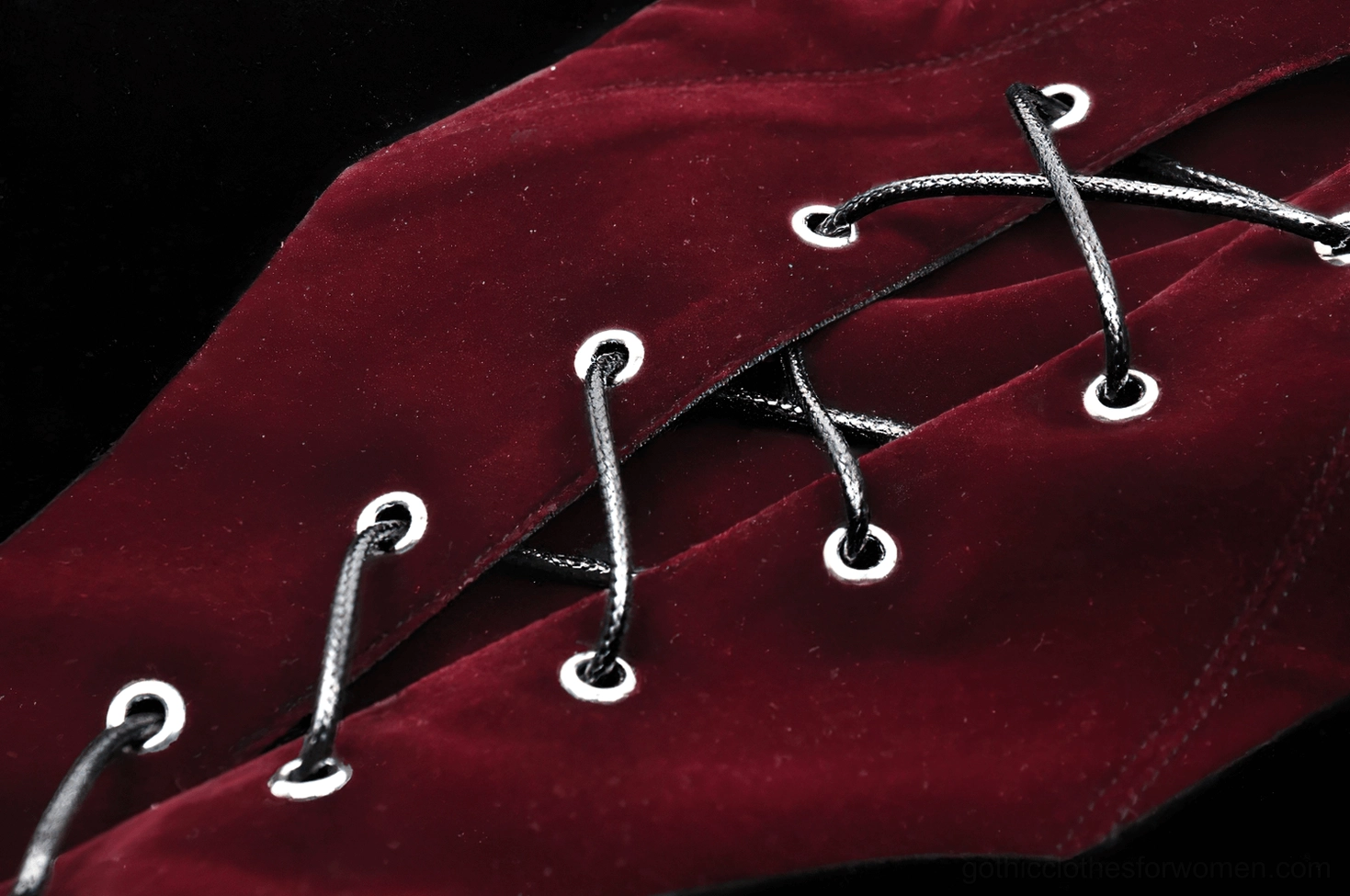 Macro close-up of gothic corset lace-up detail, metal eyelets and black lace drawstring on velvet surface