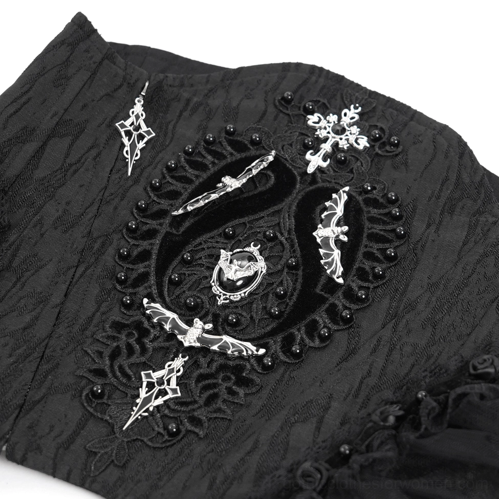 Close-up detail of gothic corset embroidery featuring cross, bat, and snake metal ornaments with beaded trim accents