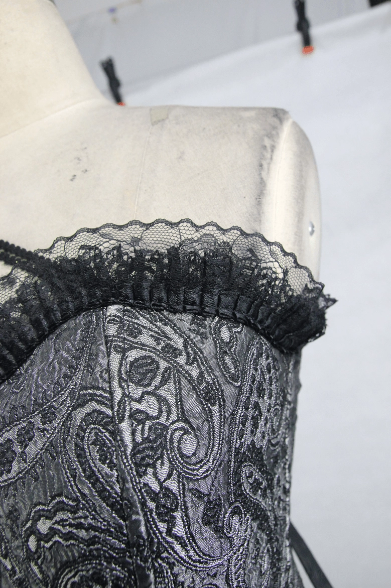 Close-up detail of gothic corset lace ruffle trim and paisley jacquard fabric neckline