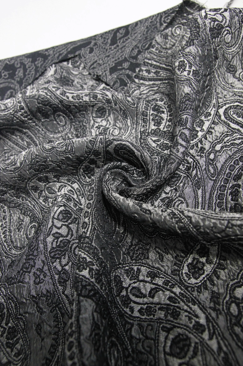 Close-up flat lay of gothic corset fabric showing paisley jacquard pattern in black and grey tones