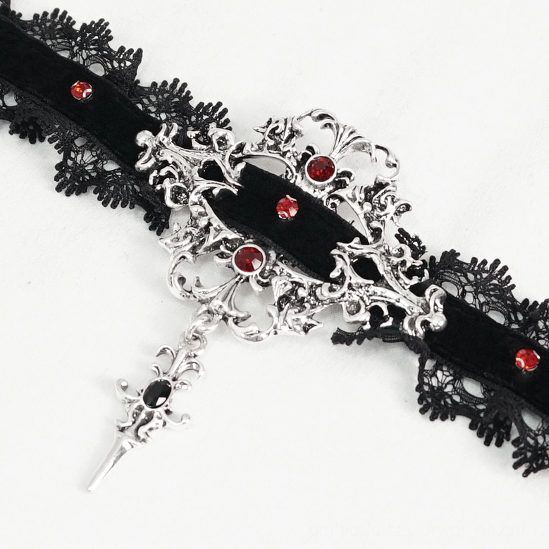 Close-up flat lay of gothic choker pendant showing ornate silver hardware, dangling cross charm with ruby red rhinestone embellishments