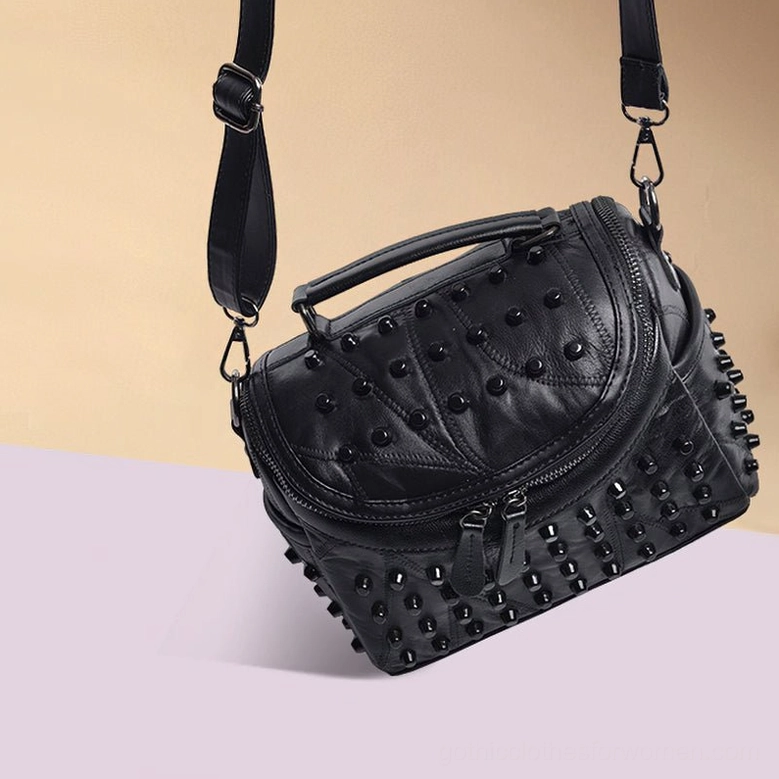Black gothic studded leather crossbody bag showing strap adjustment and functional messenger design with all-over rivet decoration