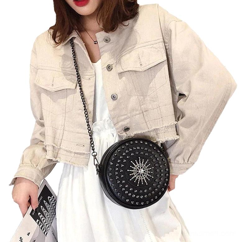 Woman wearing black studded round crossbody bag across body with beige jacket outfit