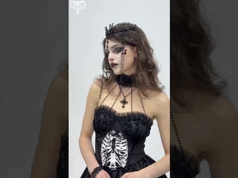 Gothic black lace crown headpiece worn by female model with skeleton print dress and black choker, three-quarter front view