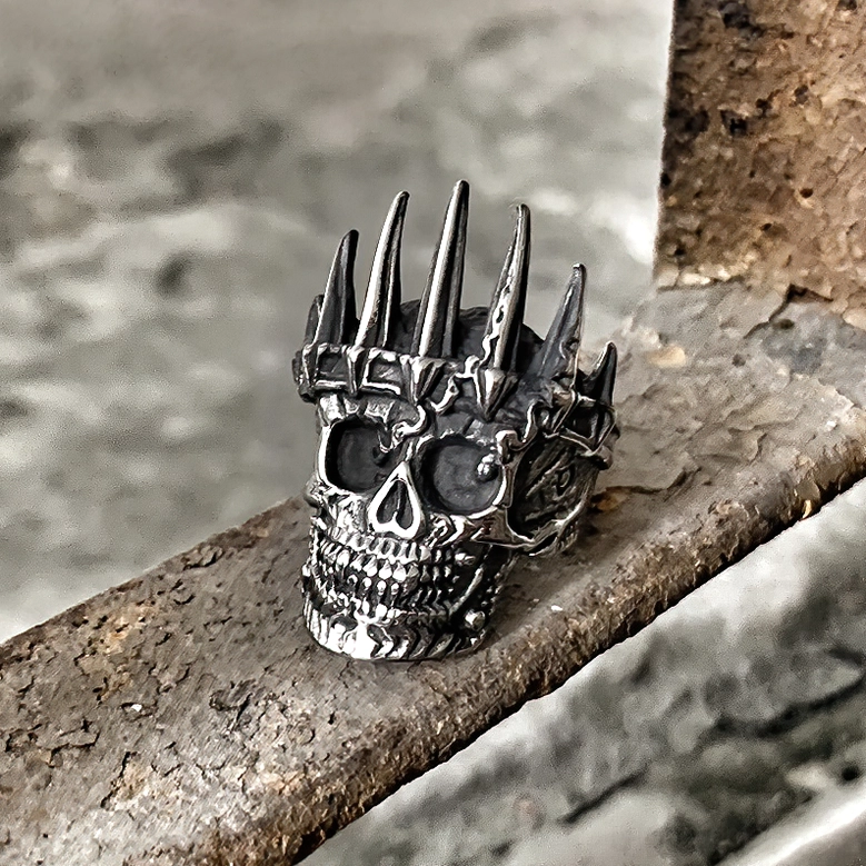 3D crowned skull gothic ring stainless steel front three-quarter view weathered dark silver metal industrial background