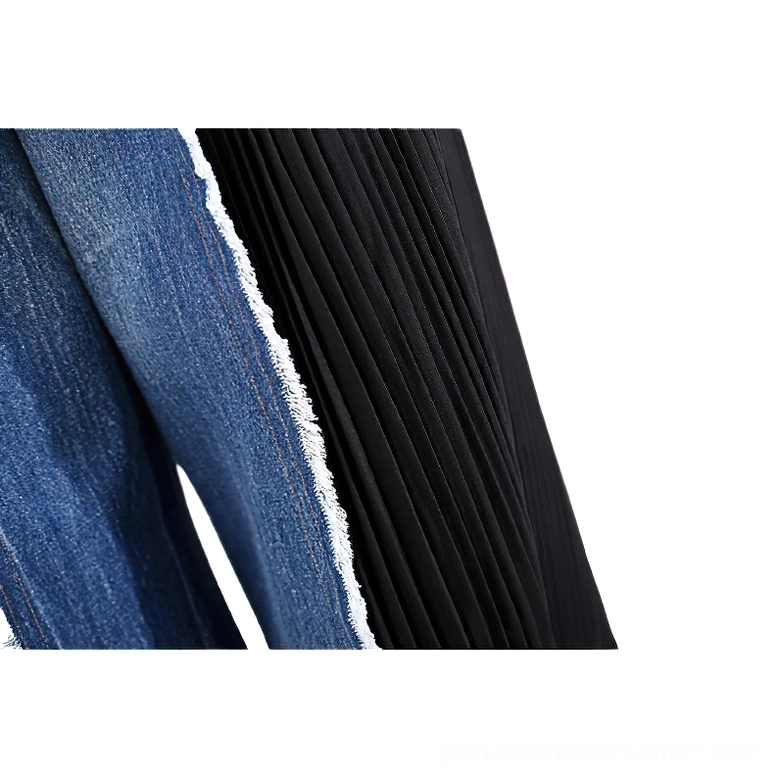Close-up detail of patchwork seam joining indigo denim fabric with black pleated panel, showcasing construction and contrast
