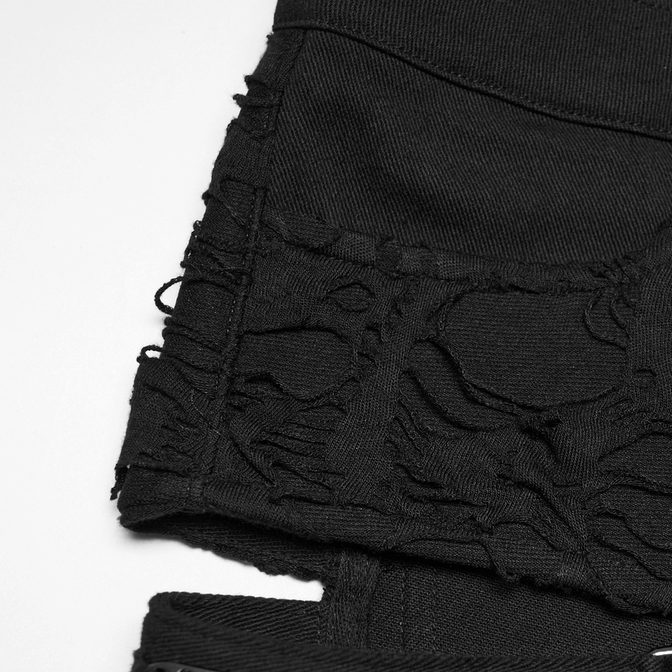Macro view of black denim fabric texture with skull-themed frayed ripped pattern