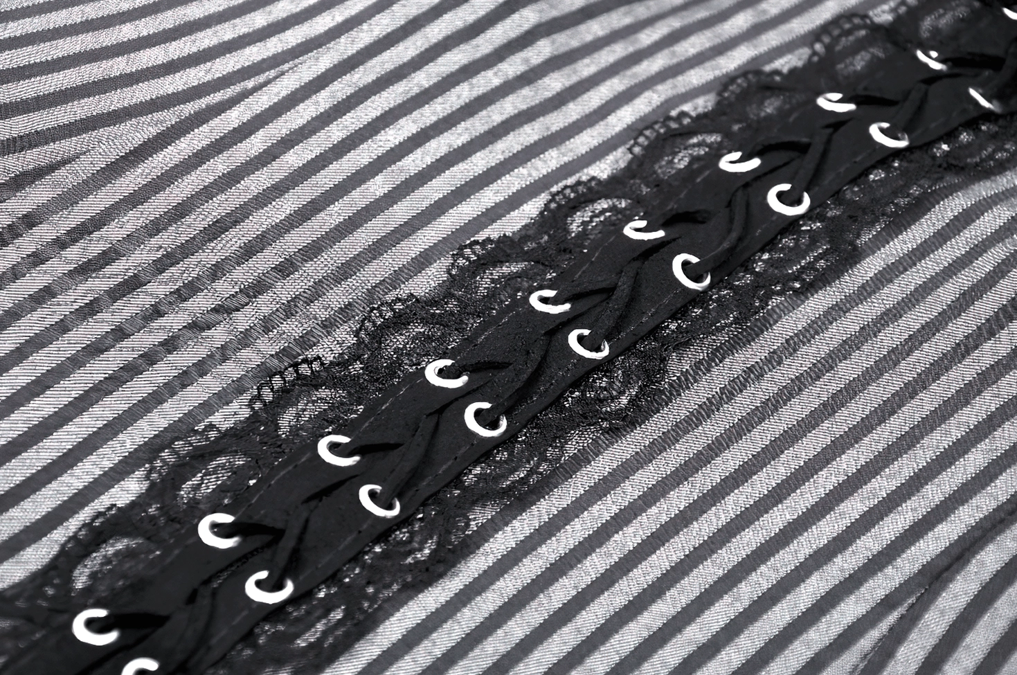 Close-up of black lace with metal eyelets and gray-black striped fabric on gothic dress front trim