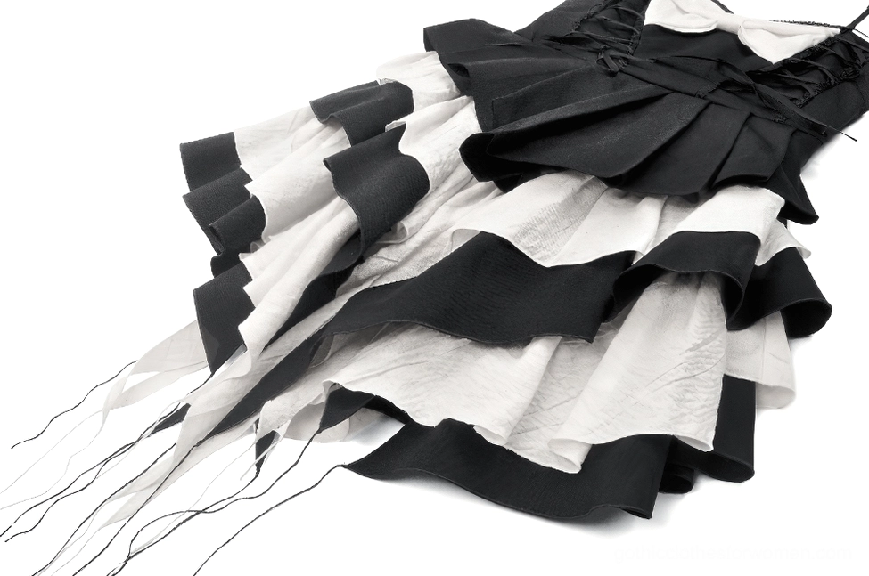 Close-up detail of tiered black and white ruffled skirt with tassel hanging trims on gothic dress