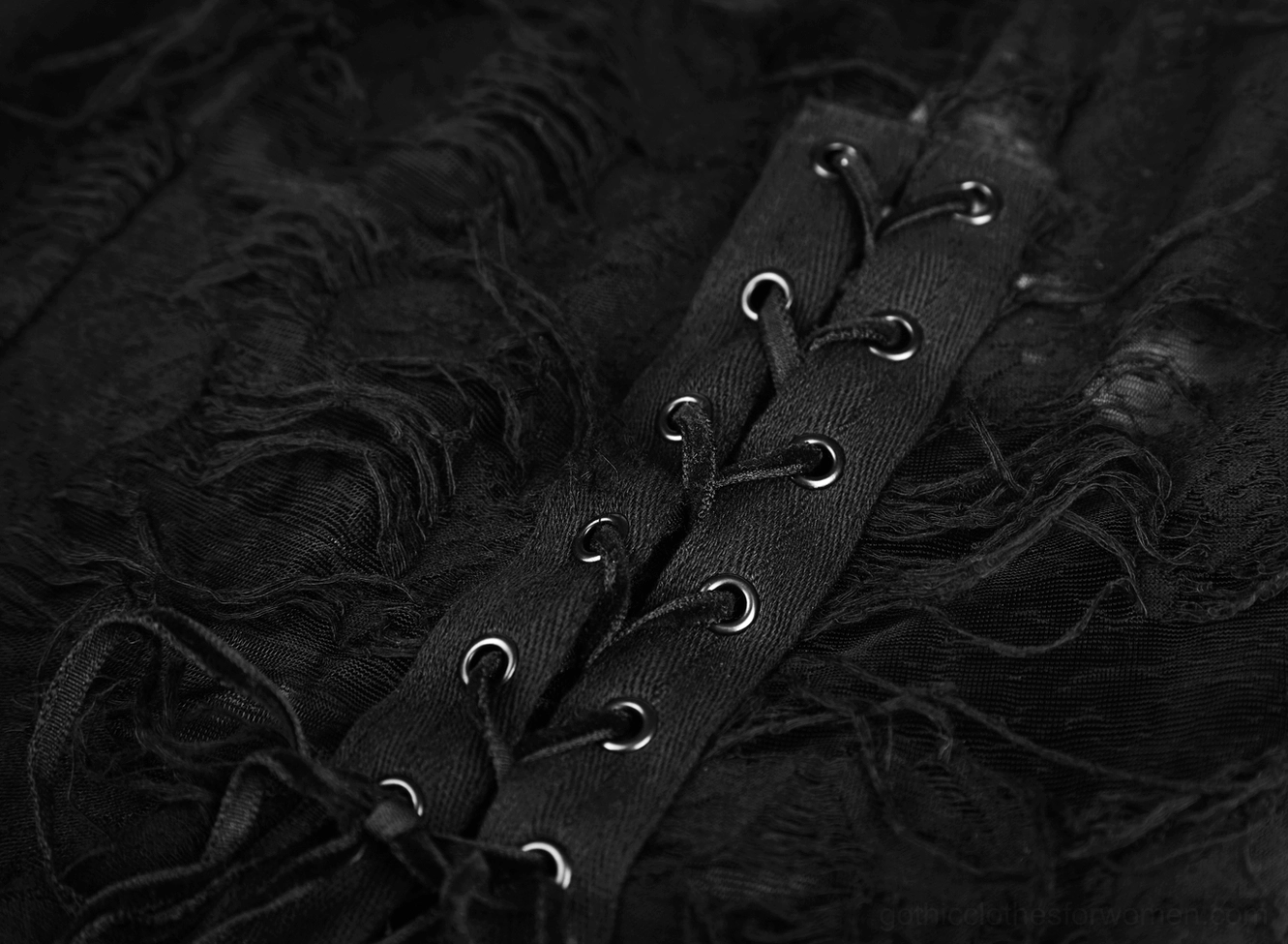 Corset-style lace-up closure detail of black gothic dress with metal eyelets and frayed black lace fabric