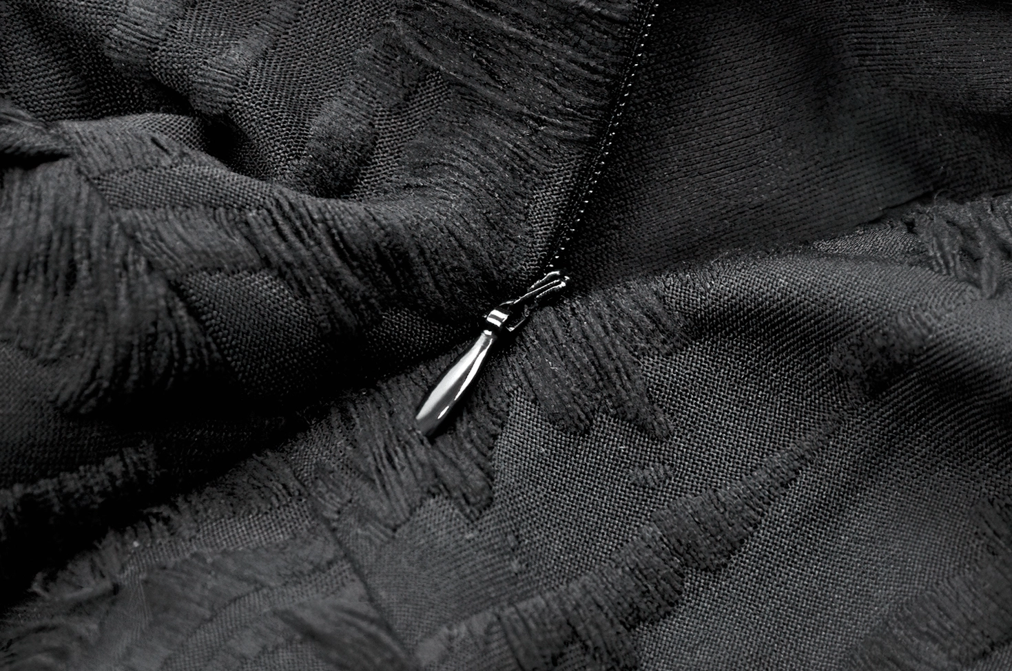 Black gothic dress fabric and hardware close-up showing jacquard texture, metal zipper, and frayed edges