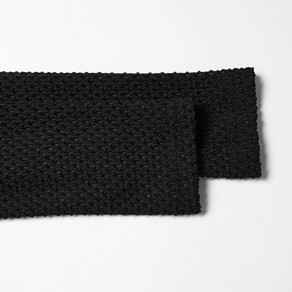 Close-up texture detail of black knitted velvet mesh fabric used in gothic dress