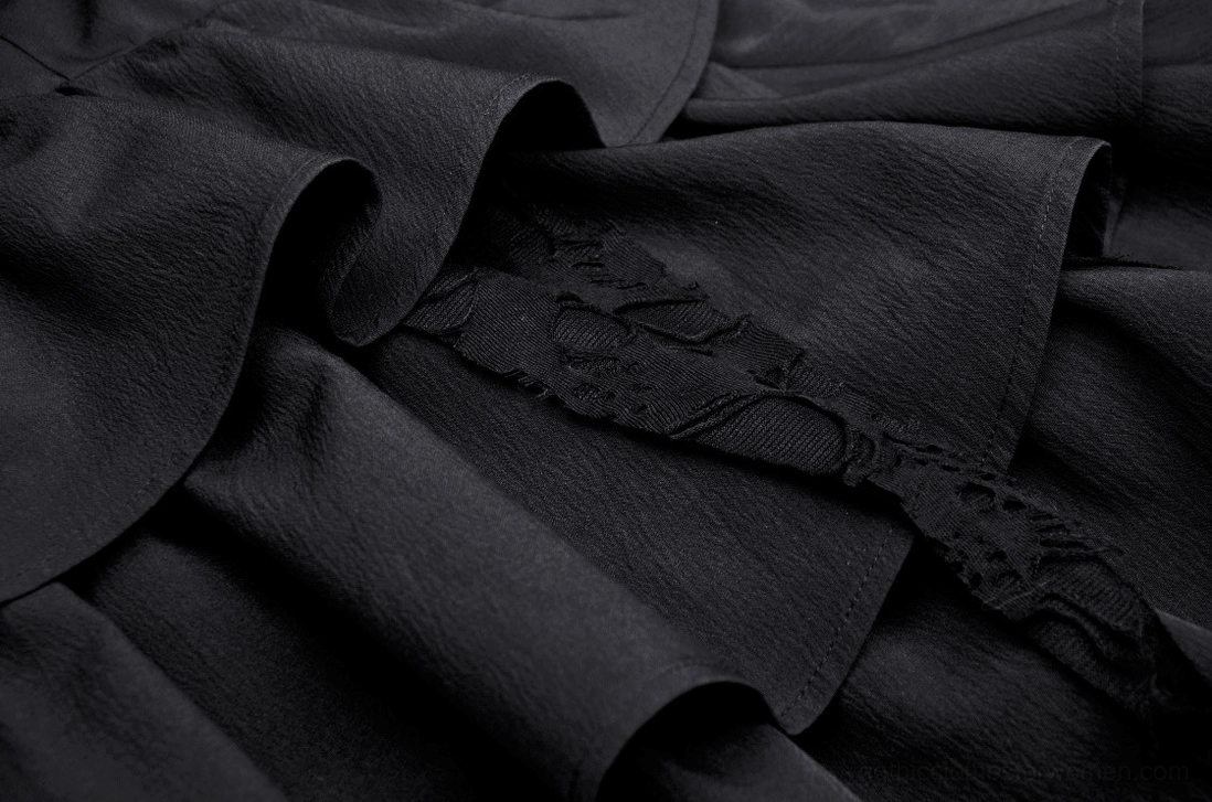 Close-up of black gothic dress matte fabric with lace appliqué texture and wrinkled finish
