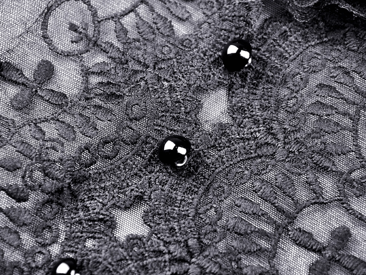 Close-up of black floral lace trim with bead embellishments and sheer mesh base on gothic dress