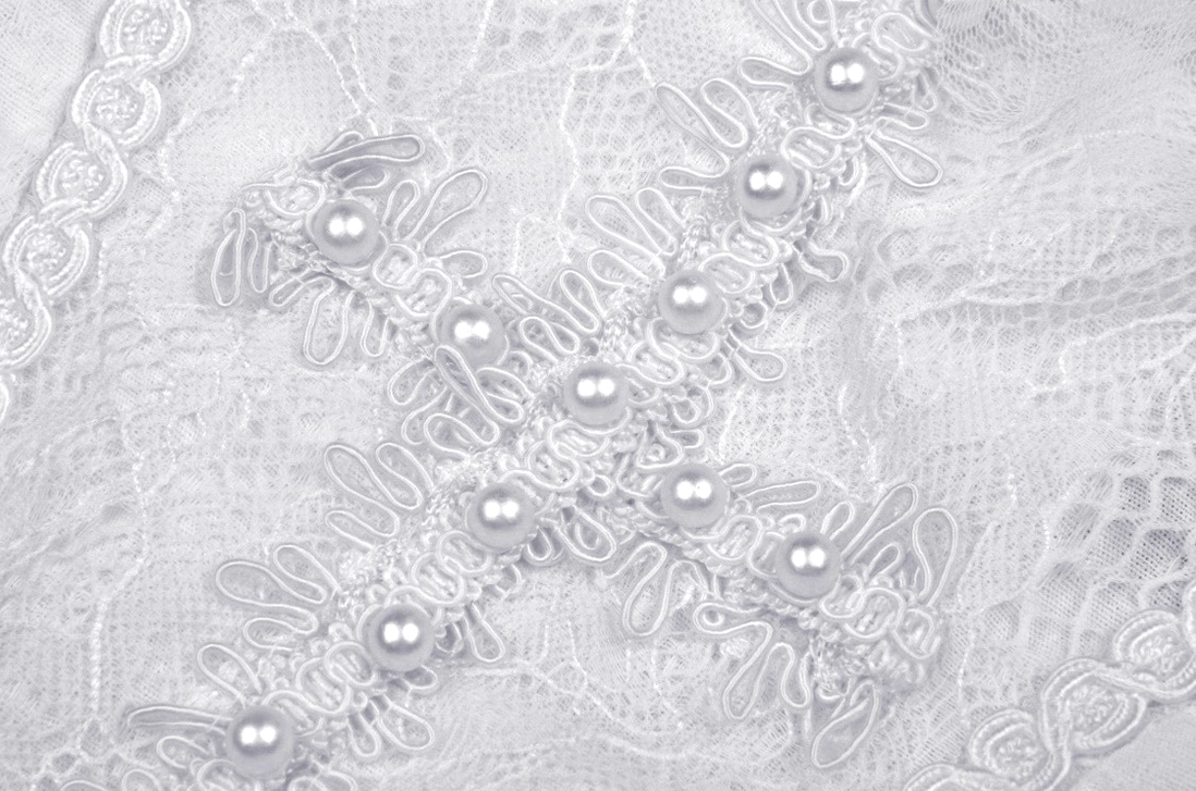 Close-up detail of white lace dress trim with faux pearls - floral lace pattern, pearl embellishments on gothic lolita mini dress