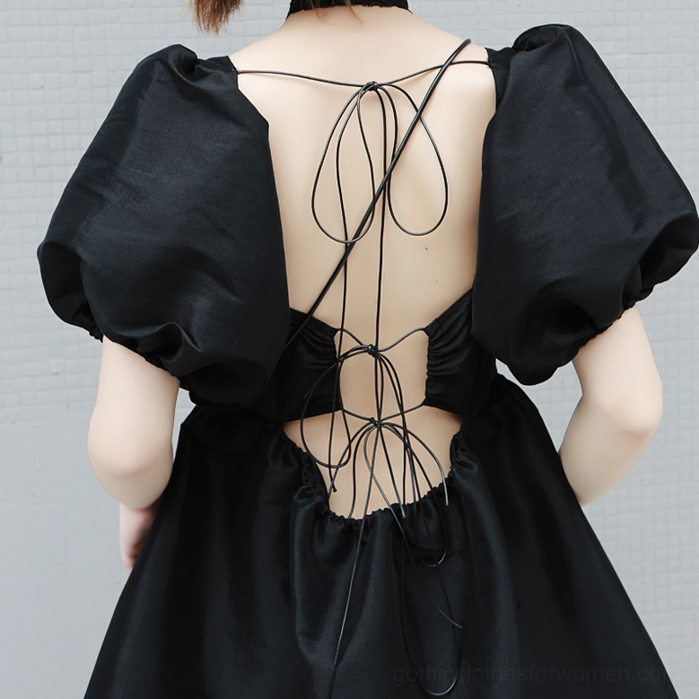 Back detail closeup of black gothic dress showing lace-up open back cutout and puff sleeves