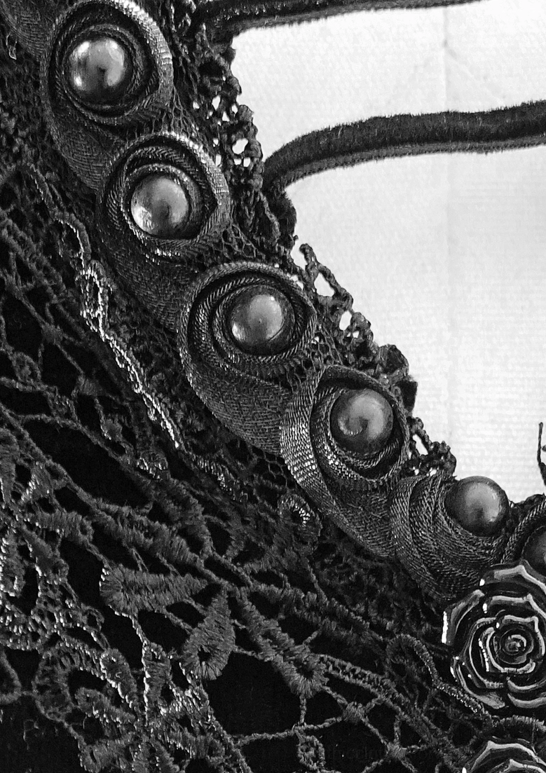 Close-up detail of gothic dress circular metal embellishments and black lace trim on velvet fabric showing craftsmanship