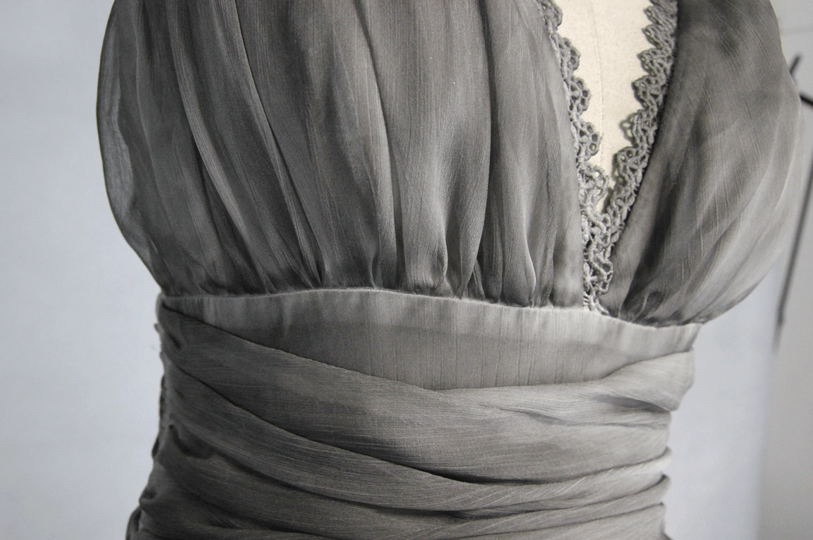 Close-up detail of gothic dress neckline and waist showing ruched fabric and lace-trimmed V neck