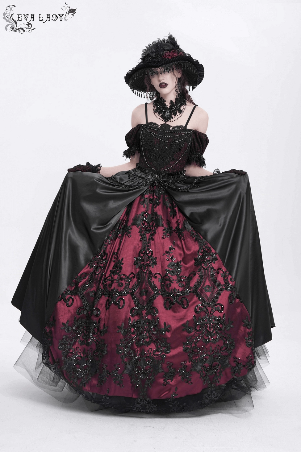 Overhead detail view of gothic dress construction showing lace work, beading application, and burgundy color blocking in the satin skirt