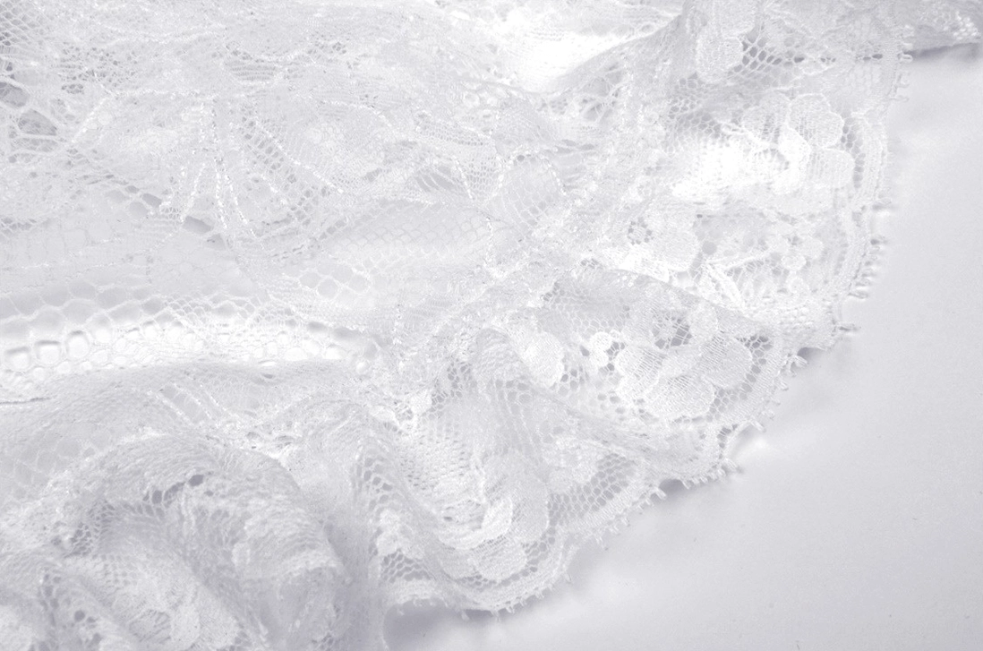 Close-up ruffled lace fabric detail - sheer texture, floral lace pattern on white gothic lolita mini dress