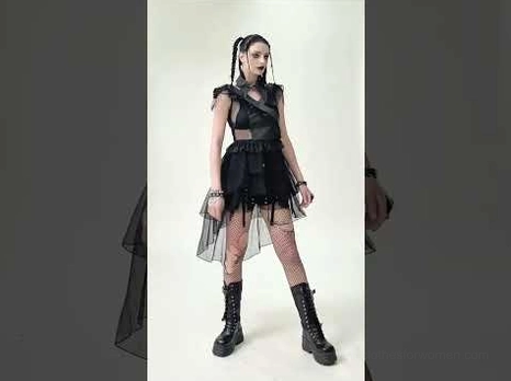 Full side profile of black gothic corset tulle dress with asymmetrical tiered skirt and platform boots against grey studio backdrop