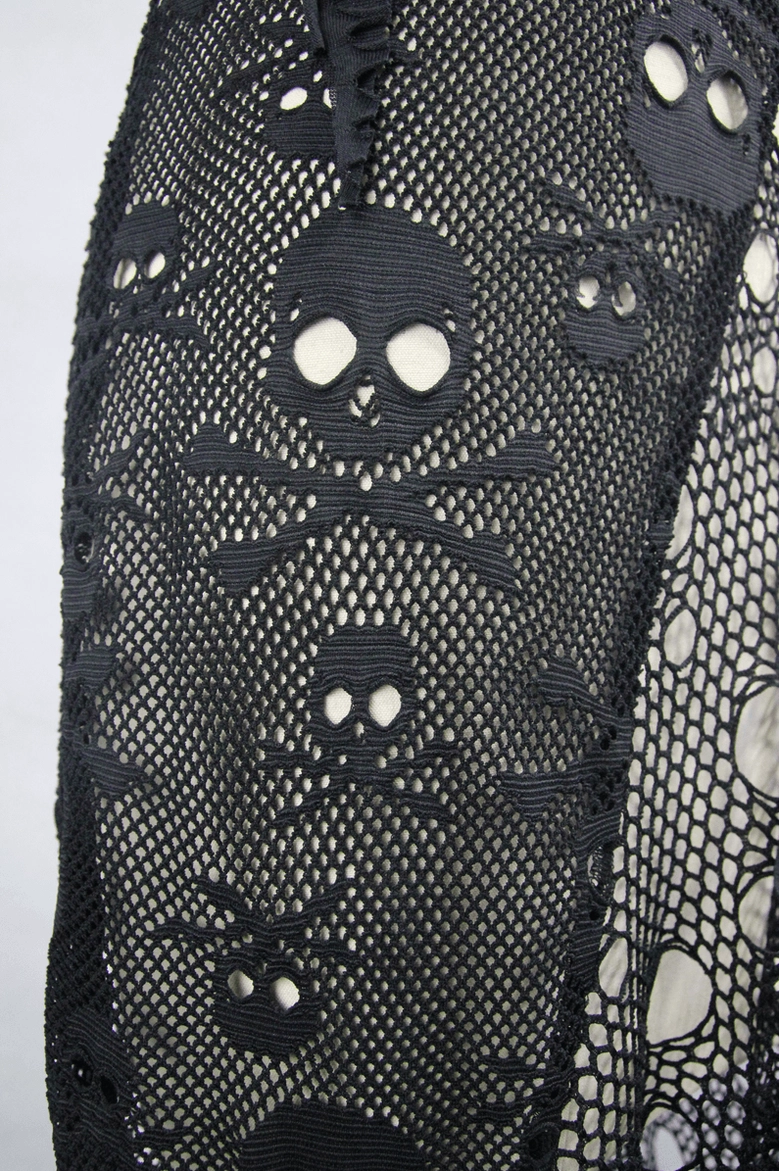 Close-up of skull and crossbone print on hexagonal mesh fishnet fabric of gothic dress
