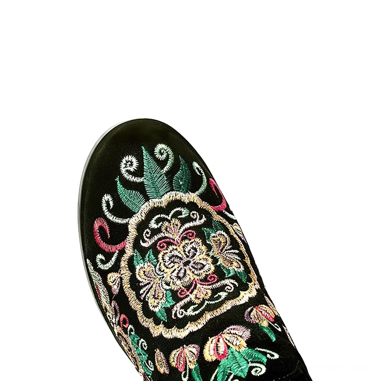 Close-up detail of gothic knee-high boot toe cap, intricate colorful floral embroidery on black leather upper