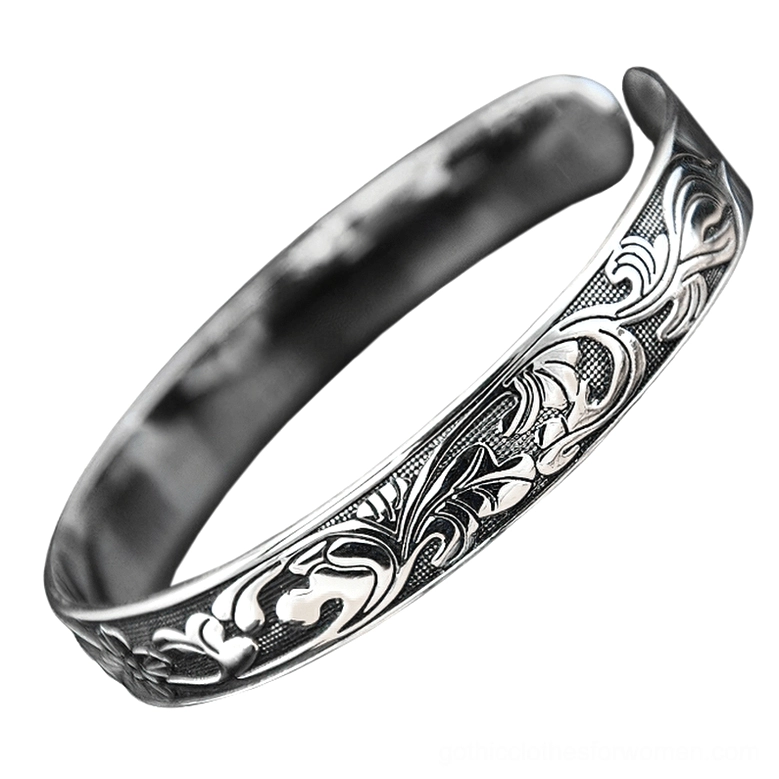Vintage open cuff bracelet side angle showing carved vine floral motifs and antiqued silver metallic finish
