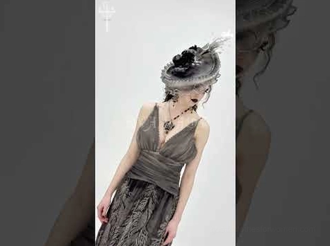 Full-body side view of gothic fascinator hat worn with elegant black formal gown ensemble