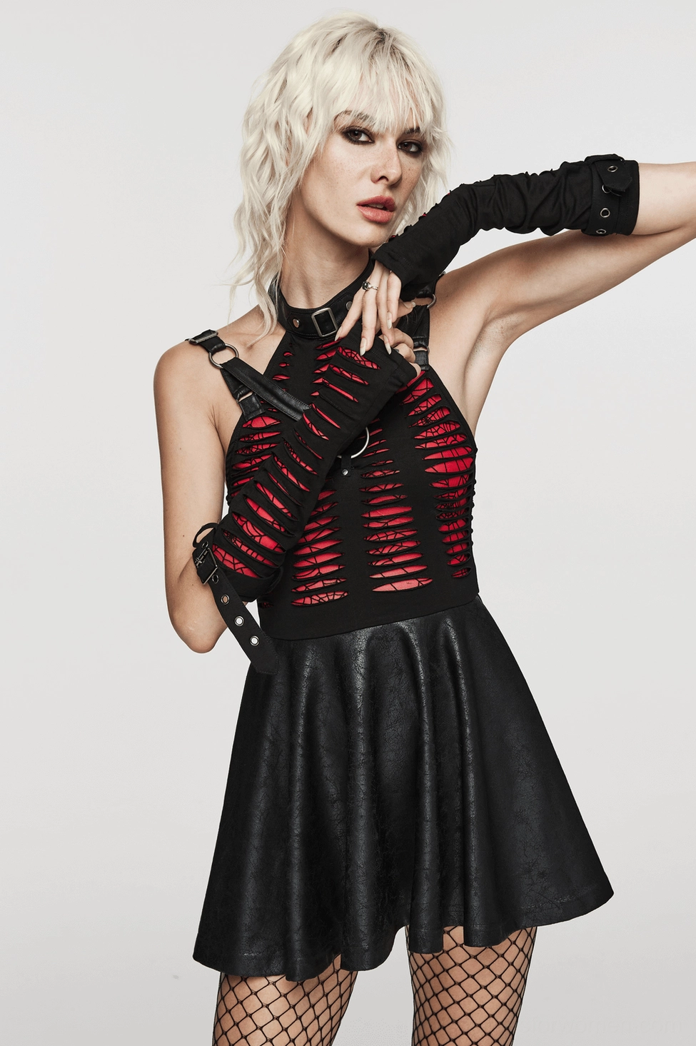 Female model wearing black and red gothic fingerless gloves as part of complete darkwave outfit with gothic top, leather skirt, and fishnet tights for alternative fashion styling