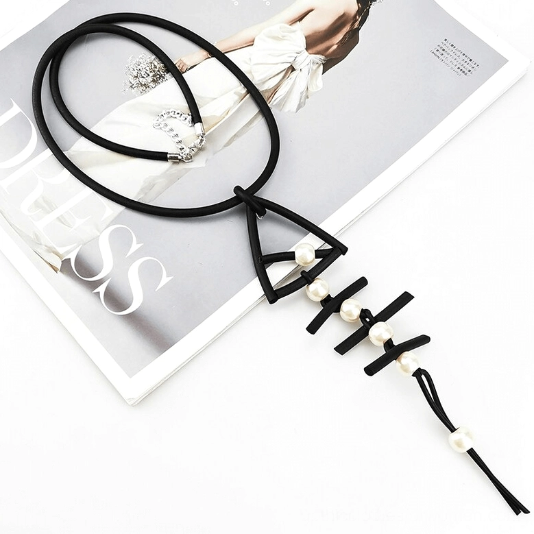 Fish bone pendant gothic necklace styled on fashion magazine background, showing black rubber cord with heart clasp and pearl accents
