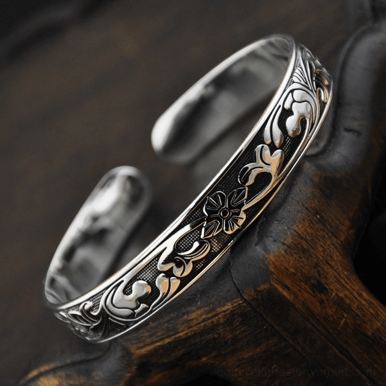 Silver ethnic floral adjustable cuff bracelet displayed on dark wood with embossed flower patterns, gothic jewelry styling