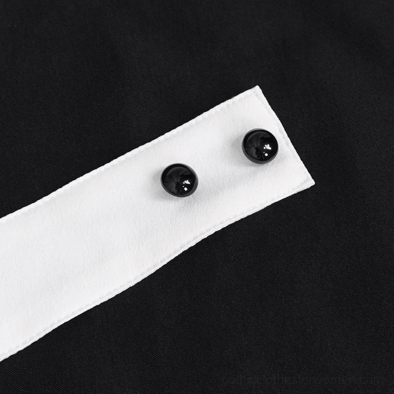 Close-up detail of gothic jabot button fasteners on white fabric strap against black background