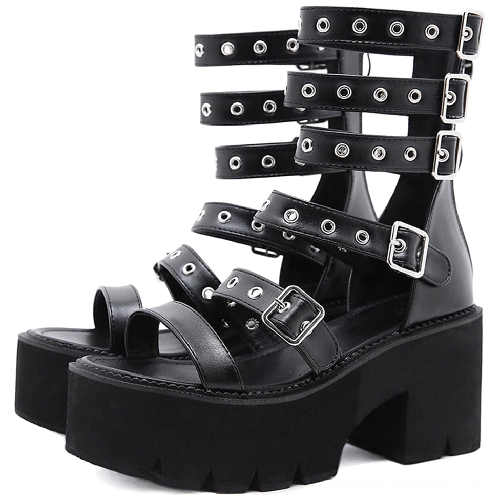 Three-quarter side view of black gladiator platform sandals pair displaying metal eyelets, rivets, chunky square block heel, and rigid structural design