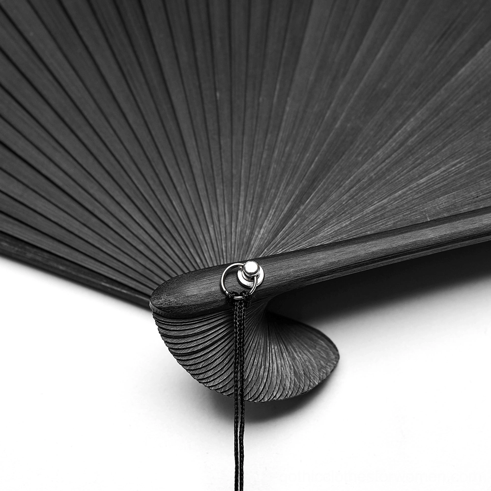 Close-up of gothic hand fan hinge joint showing silver metal loop attachment for skull tassel, curved bamboo base