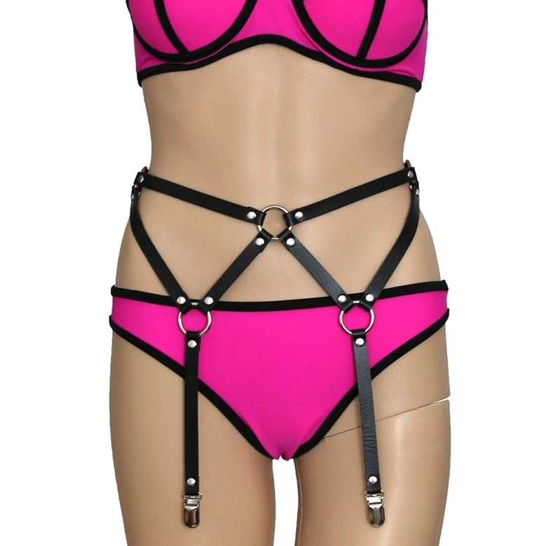 Black gothic harness on female model wearing pink lingerie, close-up front view of waist and hip area with metal hardware