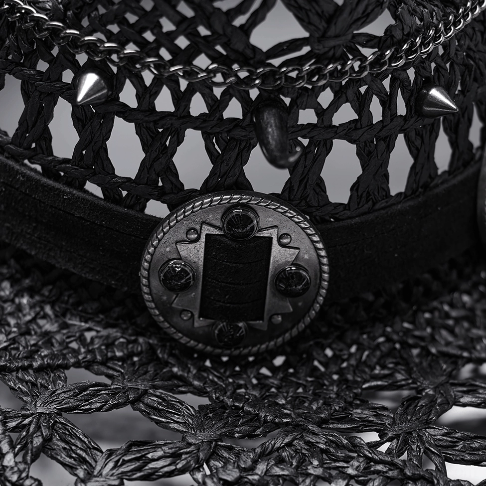 Close-up detail of black woven straw cowboy hat - metal spikes, leather band, and chain accents