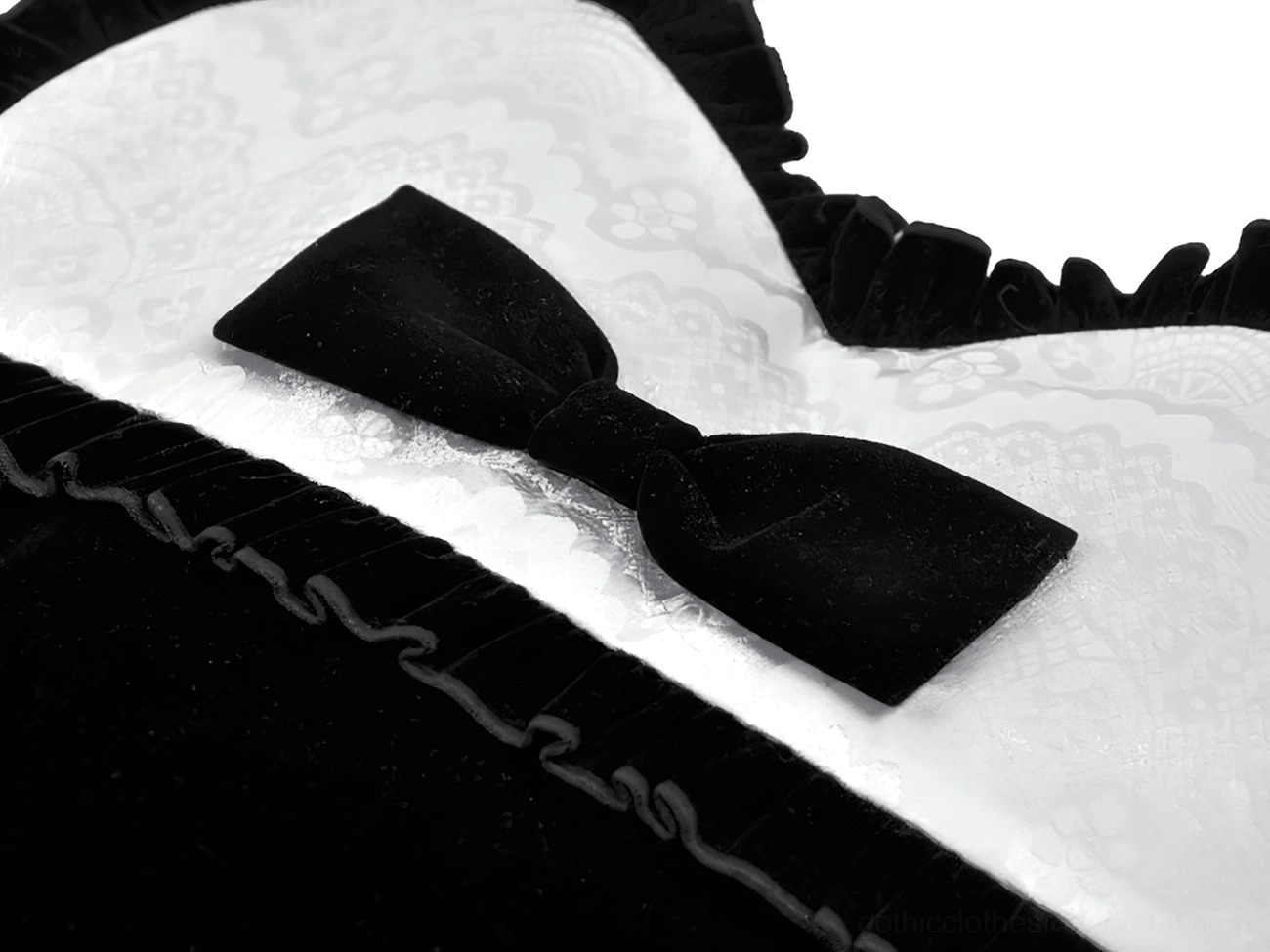 Close-up macro detail shot of black heart-shaped gothic bag showing velvet bow texture jacquard lace fabric and ruffled trim craftsmanship