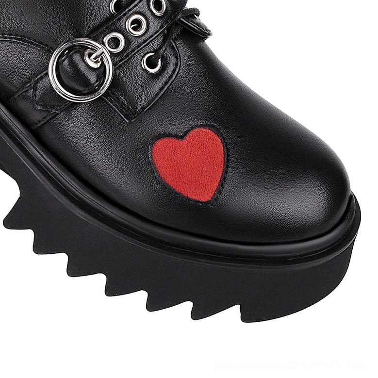 Close-up detail of black leather gothic pump vamp with red heart appliqué and jagged lug sole texture