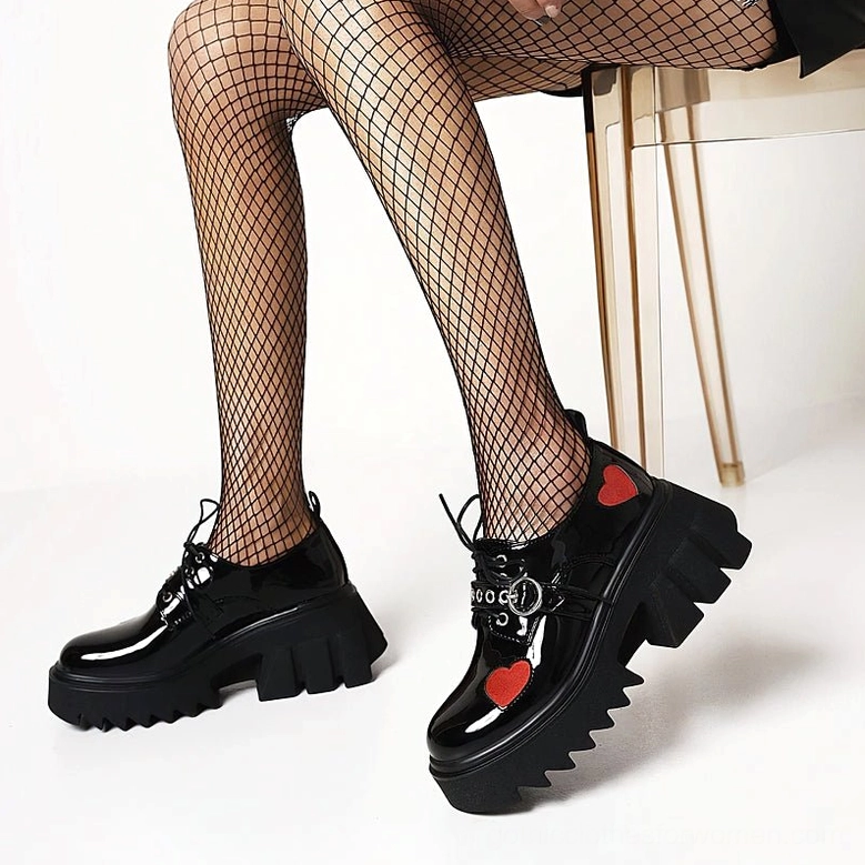 Women wearing gothic heart platform pumps with fishnet stockings, low side angle showing shoe details and chunky platform sole