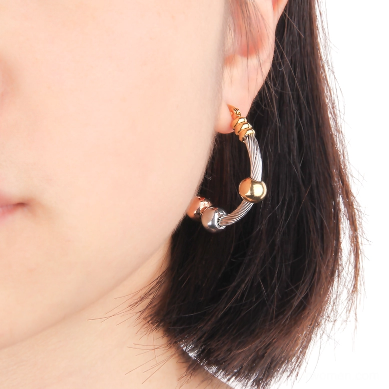 Woman wearing twisted gothic hoop earrings in profile, close-up showing dual-tone metal accents and daily wear styling