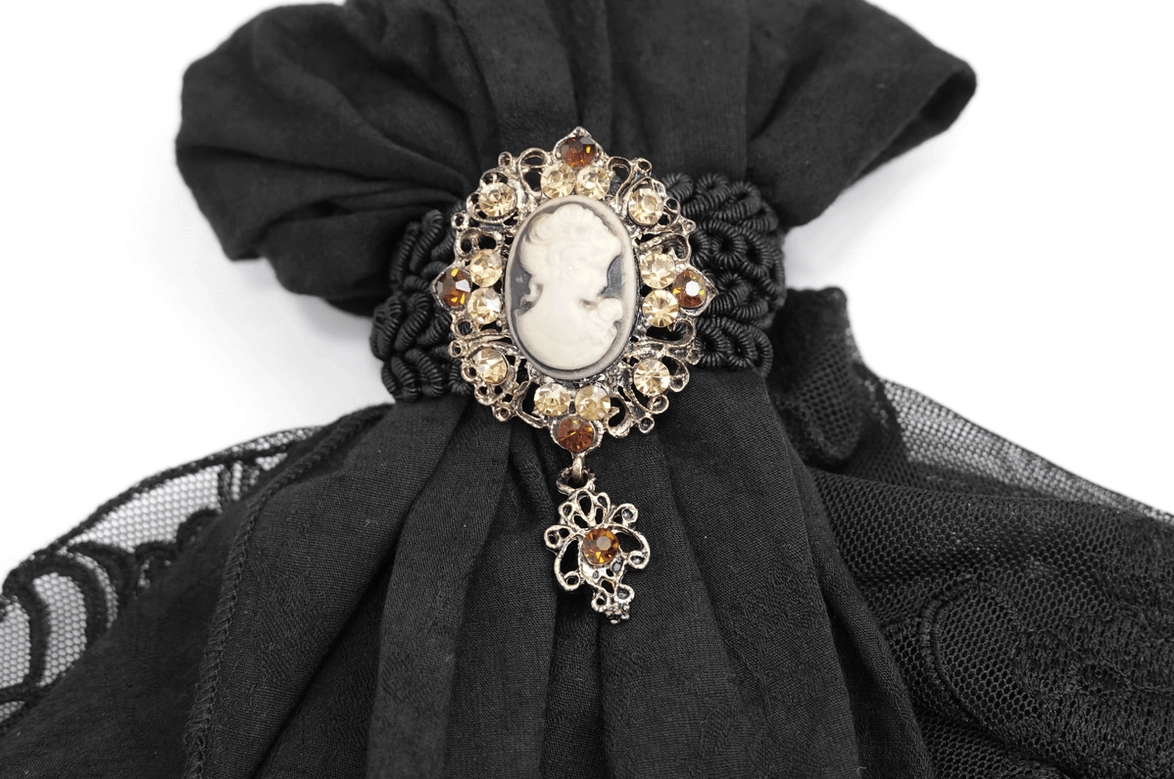 Front close-up detail of gothic lace jabot displaying ornate cameo brooch and decorative hanging charm