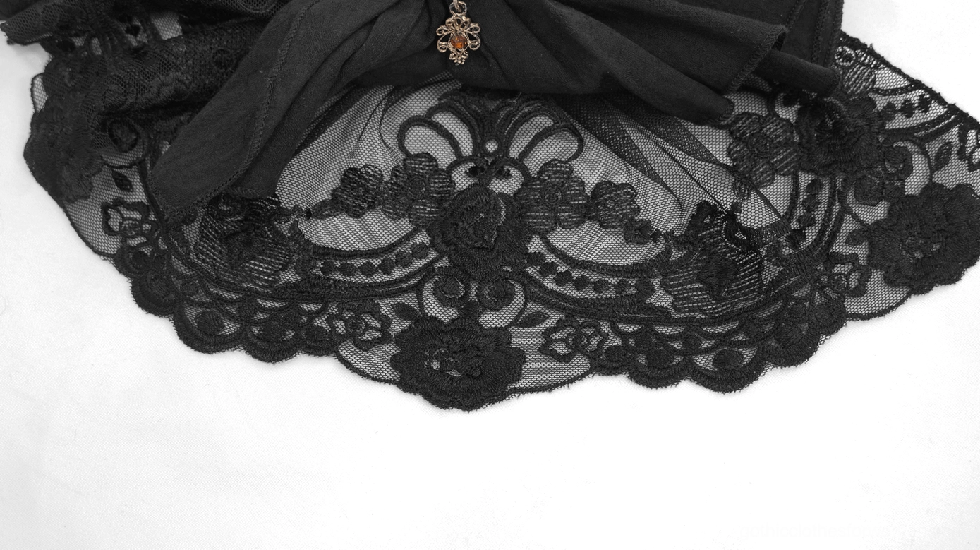Close-up flat lay of gothic jabot neckwear featuring floral lace trim and decorative hanging charm accent