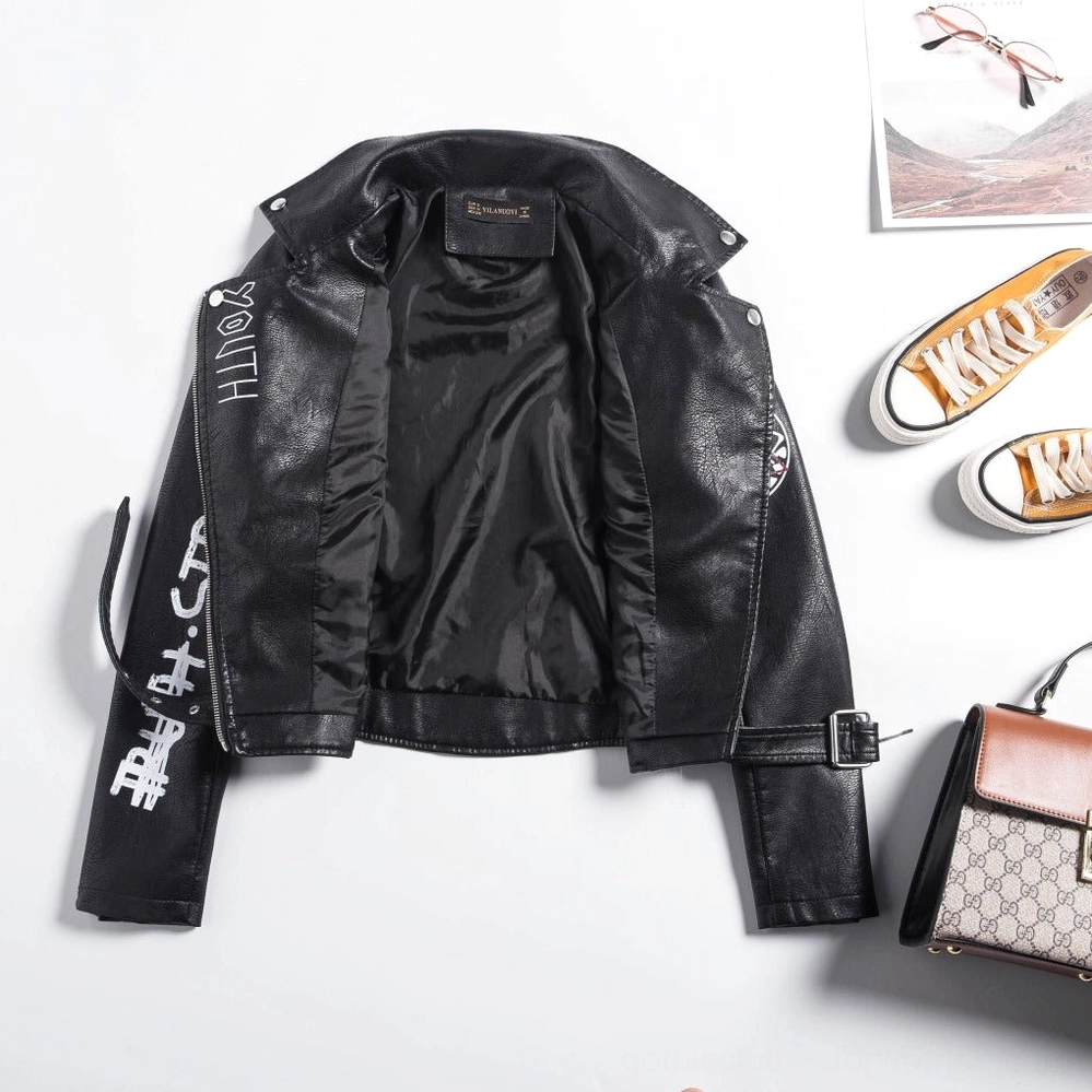Side flat lay view of black leather motorcycle jacket with visible interior lining and casual lifestyle accessories on tabletop